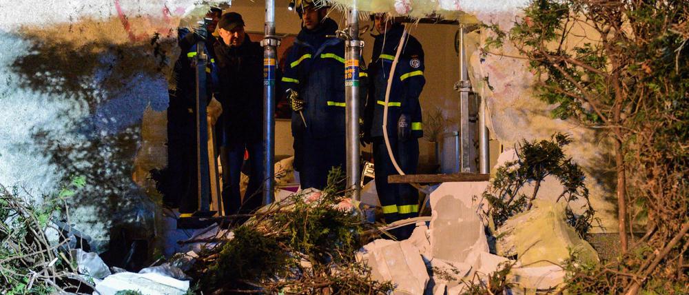 Die Feuerwehr steht hinter dem Loch in einer Hauswand, das ein Pkw gerissen hat.