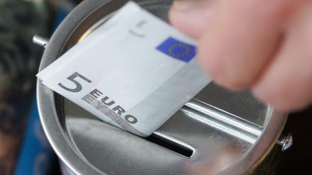 Ein Fünf-Euro-Schein wird in Witten in eine Spendendose gesteckt. 