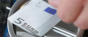 Ein Fünf-Euro-Schein wird in Witten in eine Spendendose gesteckt. 