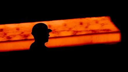 Die Silhouette eines Stahlarbeiters zeichnet sich im Werk der Salzgitter AG vor einer glühenden Bramme ab.