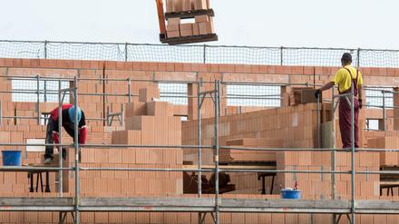 Maurer arbeiten am Rohbau von Reihenhäusern.
