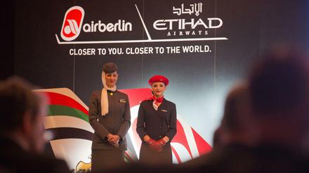 Eine Stewardess von Air Berlin (rechts) steht neben ihrer Kollegin von der Fluggesellschaft Etihad Airways im Dezember 2012 bei einer Pressekonferenz in Berlin. 
