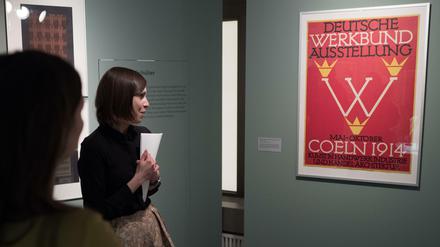 Besucher betrachten ein Plakat für die deutsche Werkbund-Ausstellung im Kunstgewerbemuseum in Berlin. Anna Teut war 1983/84 Vorsitzende des Deutschen Werkbundes. 