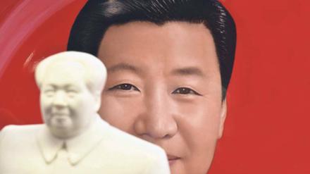 Ein Teller mit dem Bild Xi Jinpings steht in einem Pekinger Souvenirshop hinter eine Statue Mao Zedongs.