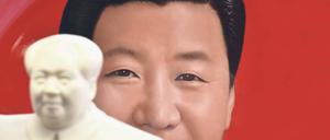 Ein Teller mit dem Bild Xi Jinpings steht in einem Pekinger Souvenirshop hinter eine Statue Mao Zedongs.