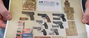 Ein Polizist hält ein Foto in der Hand, das das Ergebnis einer Aktion gegen illegalen Waffenhandel zeigt.