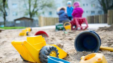 Spielzeug liegt in einem Sandkasten in einer Kindertagesstätte.