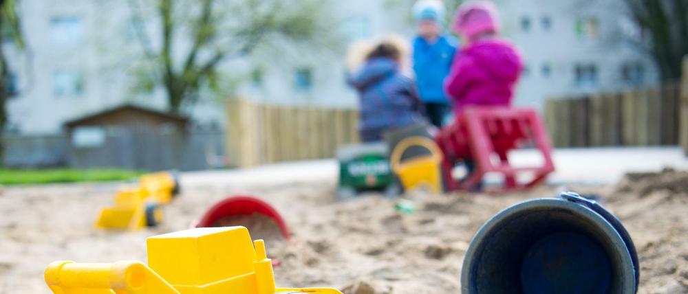 Spielzeug liegt in einem Sandkasten in einer Kindertagesstätte.
