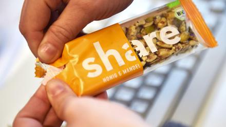 Eine Frau öffnet einen Müsli-Riegel mit der Aufschrift «Share».