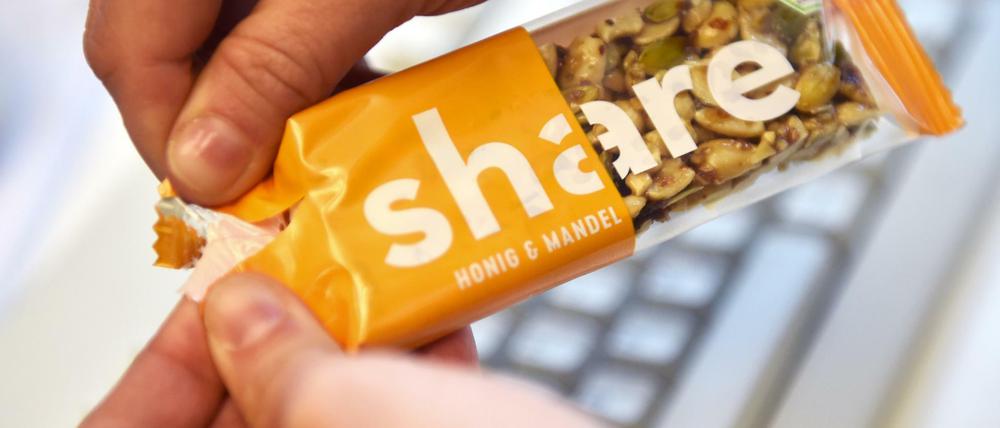 Eine Frau öffnet einen Müsli-Riegel mit der Aufschrift «Share».