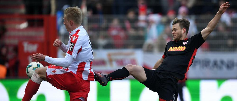 Unions Kristian Pedersen (l) und Regensburgs Benedikt Saller kämpfen um den Ball.