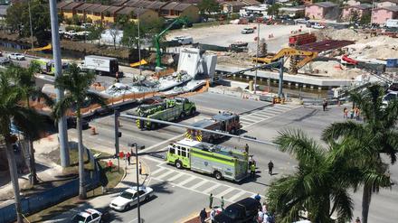 Einsatzfahrzeuge des Rettungsdienstes sperren Straßen rund um eine eingestürzte Fußgängerbrücke.