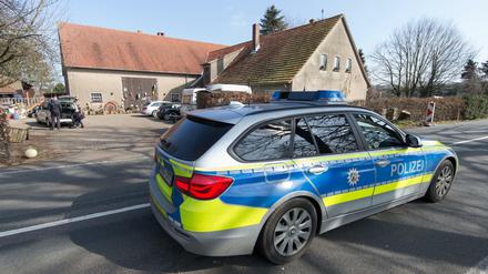 Ein Polizeiwagen fährt am Haus des Tatverdächtigen in Hille entlang. Es wurden insgesamt drei Leichen gefunden. 