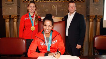 Goldmedaillen-Gewinnerinnen Mariama Jamanka (vorne) und Lisa Buckwitz tragen sich in das Goldene Buch von Reinickendorf ein.