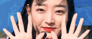 Farbenfroh. Paralympics-Volunteer. Übrigens: Zeige- und Mittelfinger gekreuzt, das wäre „Herz“. 