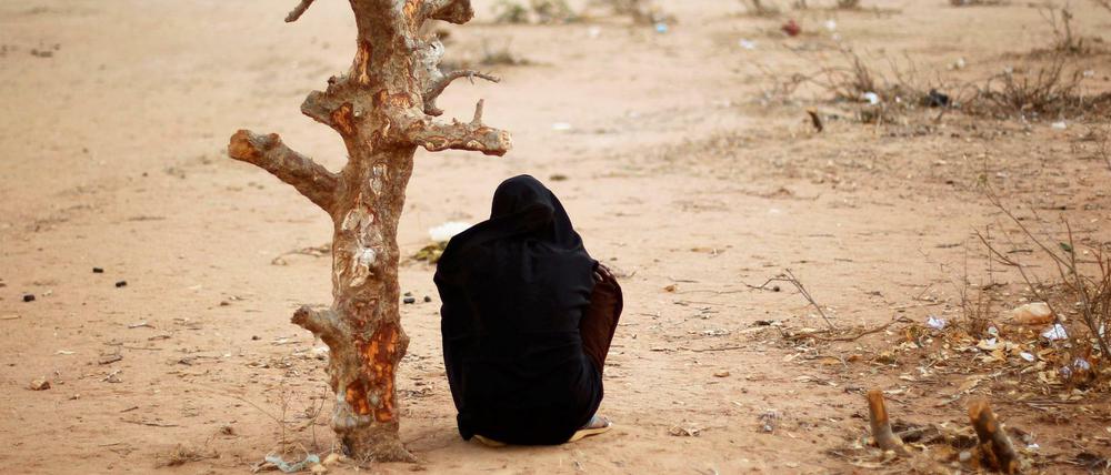 Eine Frau aus Somalia sitzt in der Nähe eines UNHCR Flüchtlingslagers in Dadaab (Kenia) an einem verdorrten Baum.