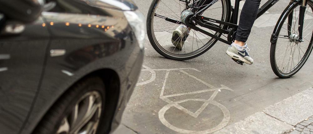 Auto parkt auf Radweg, davor fädelt sich Radfahrer ein.