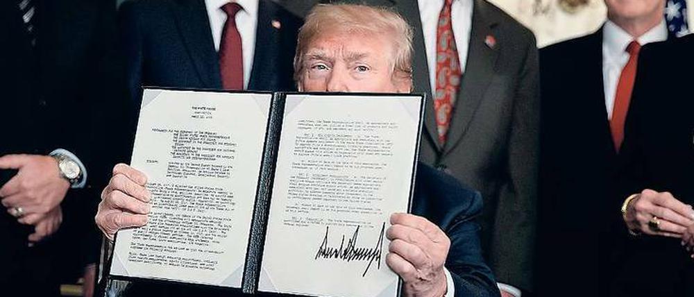 Trump zeigt das Dokument, mit dem er neue Strafzölle gegen China einführt.