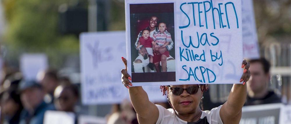 Eine Demonstrantin hält ein Schild mit einem Bild von Stephon Clark in die Höhe, der durch die Polizei erschossen wurde.