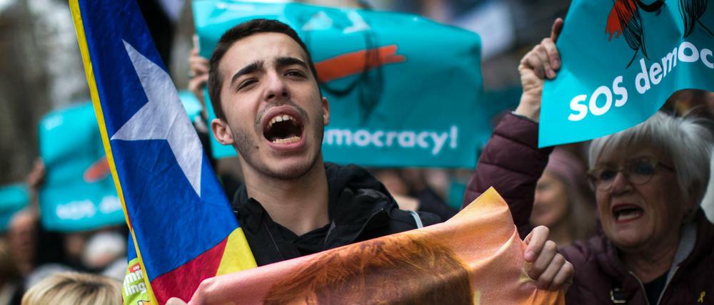 Spanien, Barcelona: Ein Demonstrant, der für die Unabhängigkeit Kataloniens ist, hält ein Poster mit einem Bild des abgesetzten ehemaligen Präsidenten der spanischen Region Katalonien Puigdemont. Der katalanische Ex-Regionalpräsident Puigdemont ist am 25.03.2018 nach der Einreise aus Dänemark in Deutschland festgenommen worden.