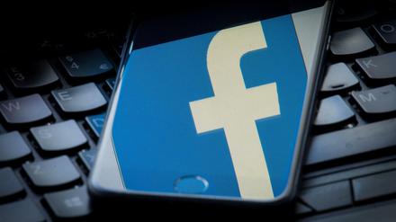 Das Logo von Facebook spiegelt sich auf einem Smartphone. 