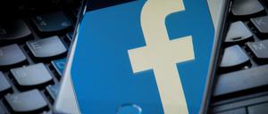 Das Logo von Facebook spiegelt sich auf einem Smartphone. 