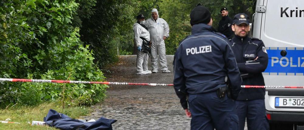 Einsatzkräfte der Polizei und Kriminaltechniker stehen in der Nähe des Tatorts.