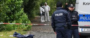Einsatzkräfte der Polizei und Kriminaltechniker stehen in der Nähe des Tatorts.
