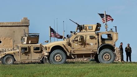 Soldaten stehen im syrischen Manbidsch neben Militärfahrzeugen über denen US-amerikanische Fahnen wehen. Am Donnerstag waren dort ein amerikanischer und ein britischer Soldat getötet worden.