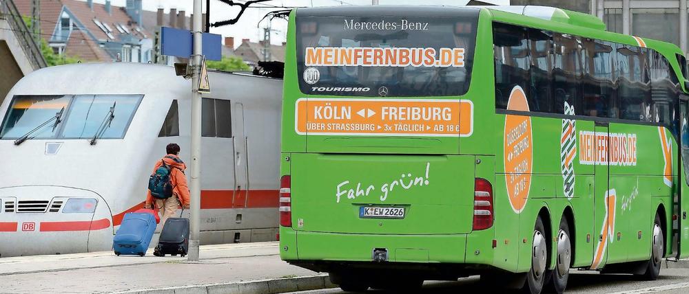Ein Fernbus neben einem ICE-Zug der Deutschen Bahn.