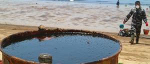 Ein Mann hilft bei der Reinigung des Benua Patra Strandes auf Borneo. Die indonesische Regierung gibt Entwarnung - der Ölteppich vor der Küste sei deutlich kleiner geworden.