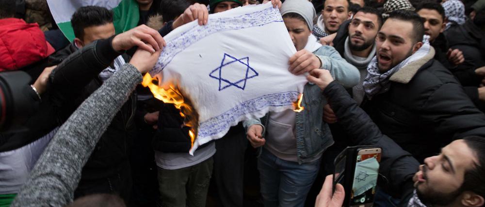 Teilnehmer einer Demonstration verbrennen am 10.12.2017 eine selbstgemalte Fahne mit einem Davidstern in Berlin im Stadtteil Neukölln.