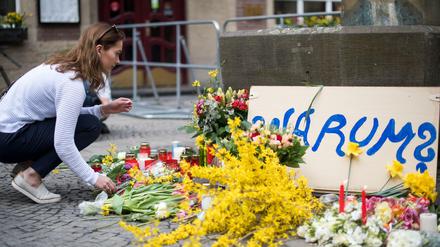 Eine Frau legt am Tatort in Münster Blumen nieder.