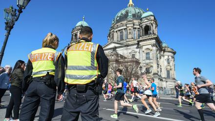 Zwei Polizisten stehen an der Halbmarathonstrecke in Berlin vor dem Dom.