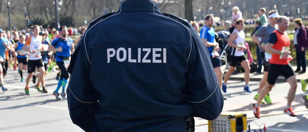 Berliner Halbmarathon, in Berlin. Ein Polizeibeamter steht an der Laufstrecke.