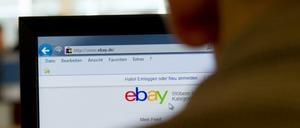 Ein Mann sitzt vor einem Computerbildschirm, auf dem die Ebay-Startseite angezeigt wird.