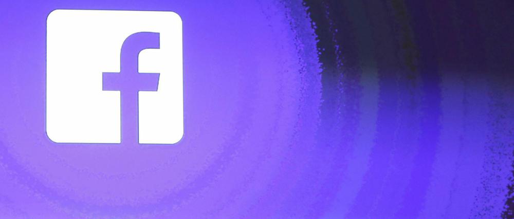 Mark Zuckerberg, Gründer von Facebook, geht am Firmensitz an einem leuchtenden Facebook logo vorbei.