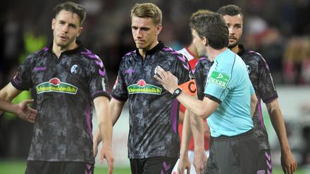 Schiedsrichter Guido Winkmann spricht mit den Freiburger Spielern Christian Günter (l-r), Nils Petersen, Manuel Gulde. 