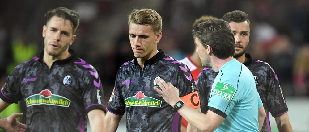 Schiedsrichter Guido Winkmann spricht mit den Freiburger Spielern Christian Günter (l-r), Nils Petersen, Manuel Gulde. 