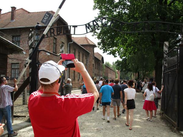 Banalisierung des Bösen. Tourist fotografiert das Tor des ehemaligen Konzentrationslagers Auschwitz.