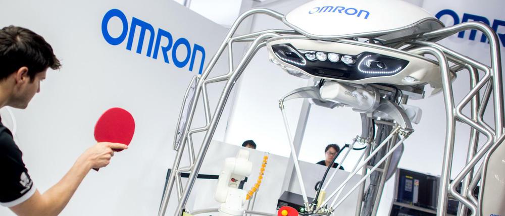 Tischtennisspieler Dimitrij Ovtcharov spielt bei der Hannover Messe am Stand von Omron gegen einen Roboter.