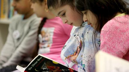 Grundschülerinnen lesen im Leseclub ihrer Schule "Die kleine Hexe".
