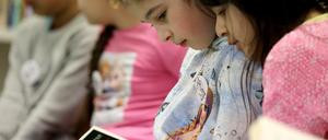Grundschülerinnen lesen im Leseclub ihrer Schule "Die kleine Hexe".