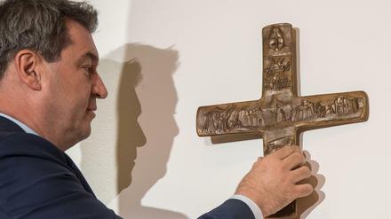 Markus Söder hängt ein Kreuz im Eingangsbereich der bayerischen Staatskanzlei auf.