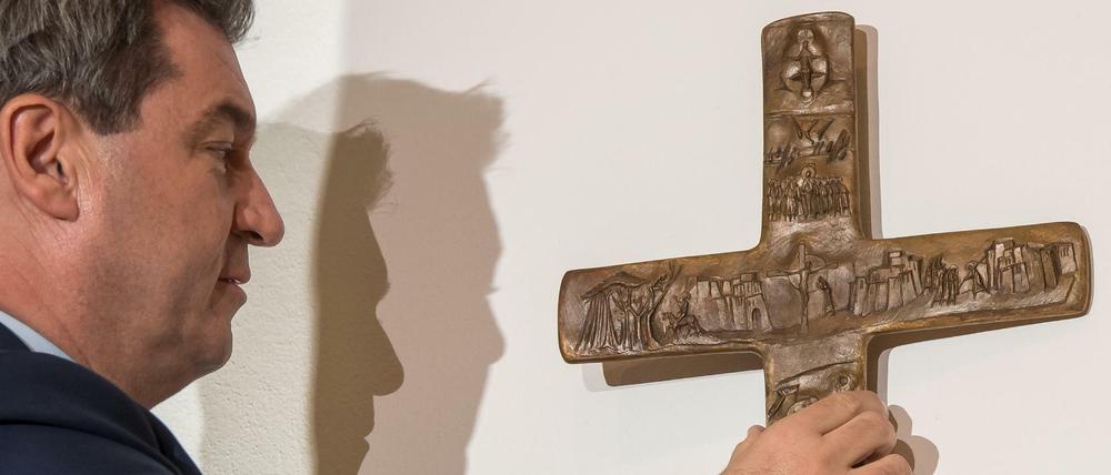 Markus Söder hängt ein Kreuz im Eingangsbereich der bayerischen Staatskanzlei auf.
