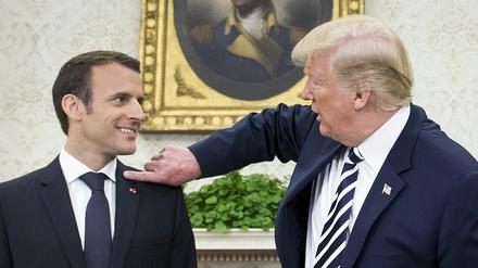US-Präsident Donald Trump wischt dem französischen Präsidenten Emmanuel Macron eine Schuppe vom Anzug.