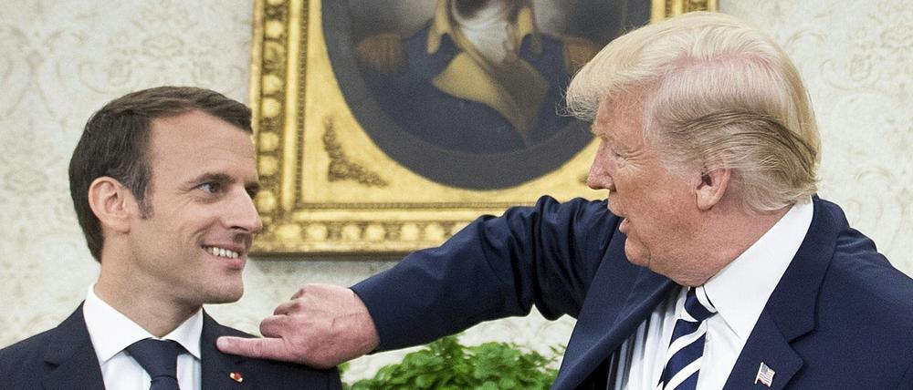 US-Präsident Donald Trump wischt dem französischen Präsidenten Emmanuel Macron eine Schuppe vom Anzug.