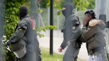 Ein Mann in Ellwangen wird von maskierten Polizisten eskortiert