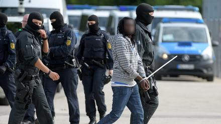 In der Landeserstaufnahmeeinrichtung für Flüchtlinge (LEA) in Ellwangen wird ein gefesselter Mann von maskierten Polizisten abgeführt. 