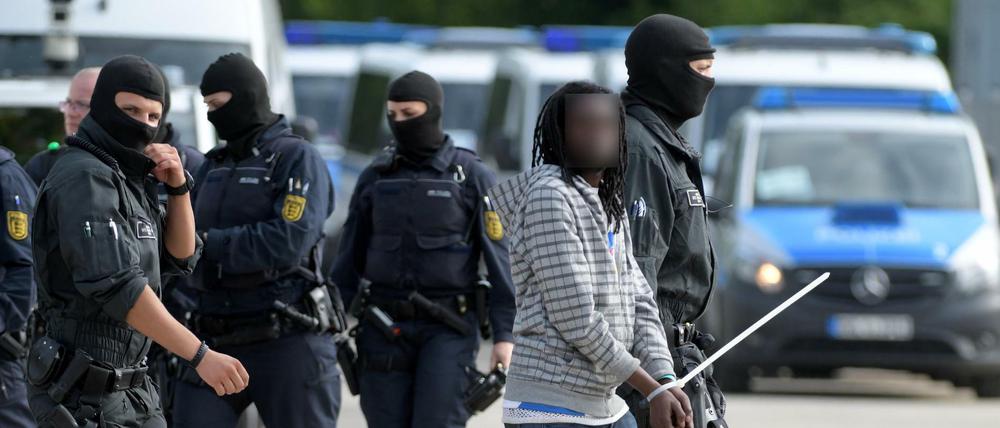 In der Landeserstaufnahmeeinrichtung für Flüchtlinge (LEA) in Ellwangen wird ein gefesselter Mann von maskierten Polizisten abgeführt.